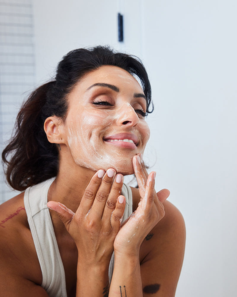 Woman gently applying Fresh Start Duo cleanser on face in bathroom setting gallery position 1