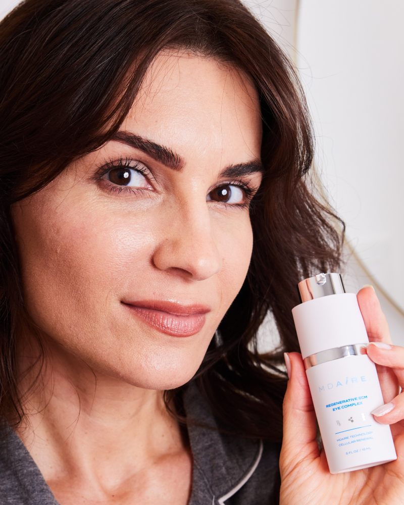 Woman holding Regenerative ECM Eye Complex bottle in gallery position 1, showcasing MDAiRE skincare product for under-eye care