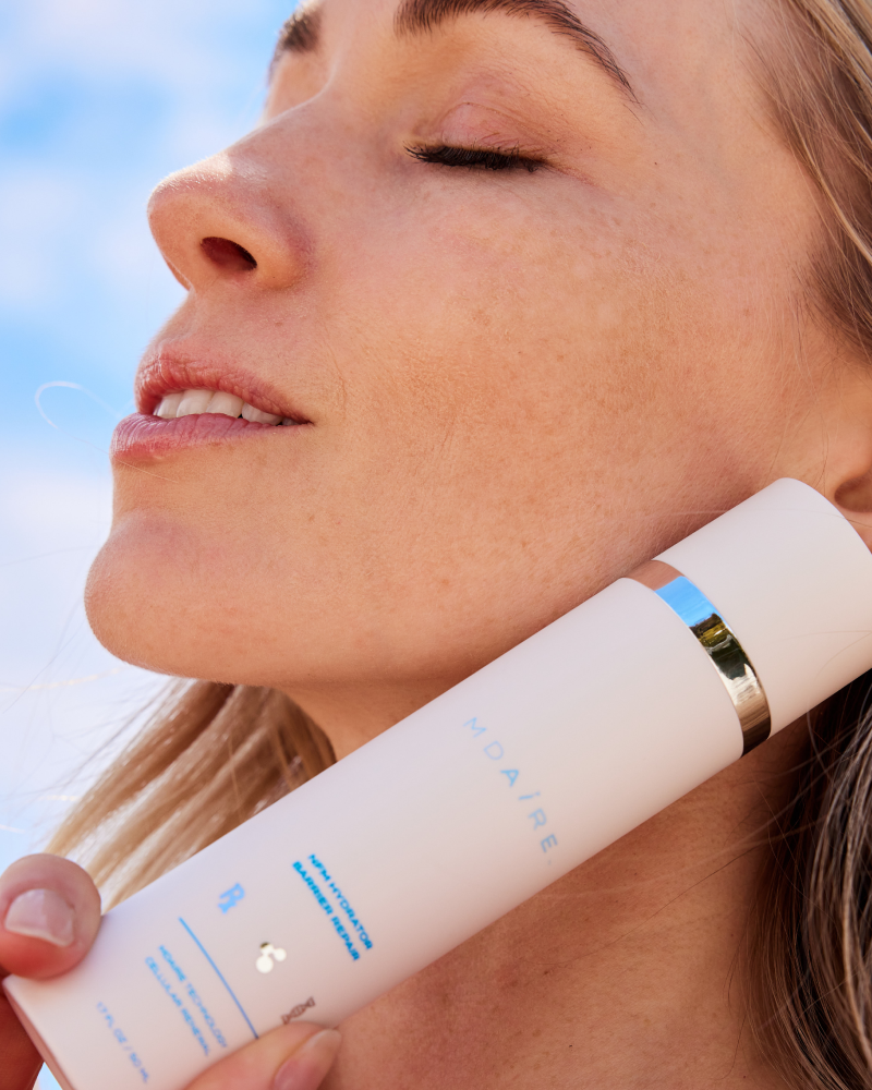 Close-up of woman holding NMF Hydrator Barrier Repair by Dr. Stefani Kappel for healthy skin from within and barrier support