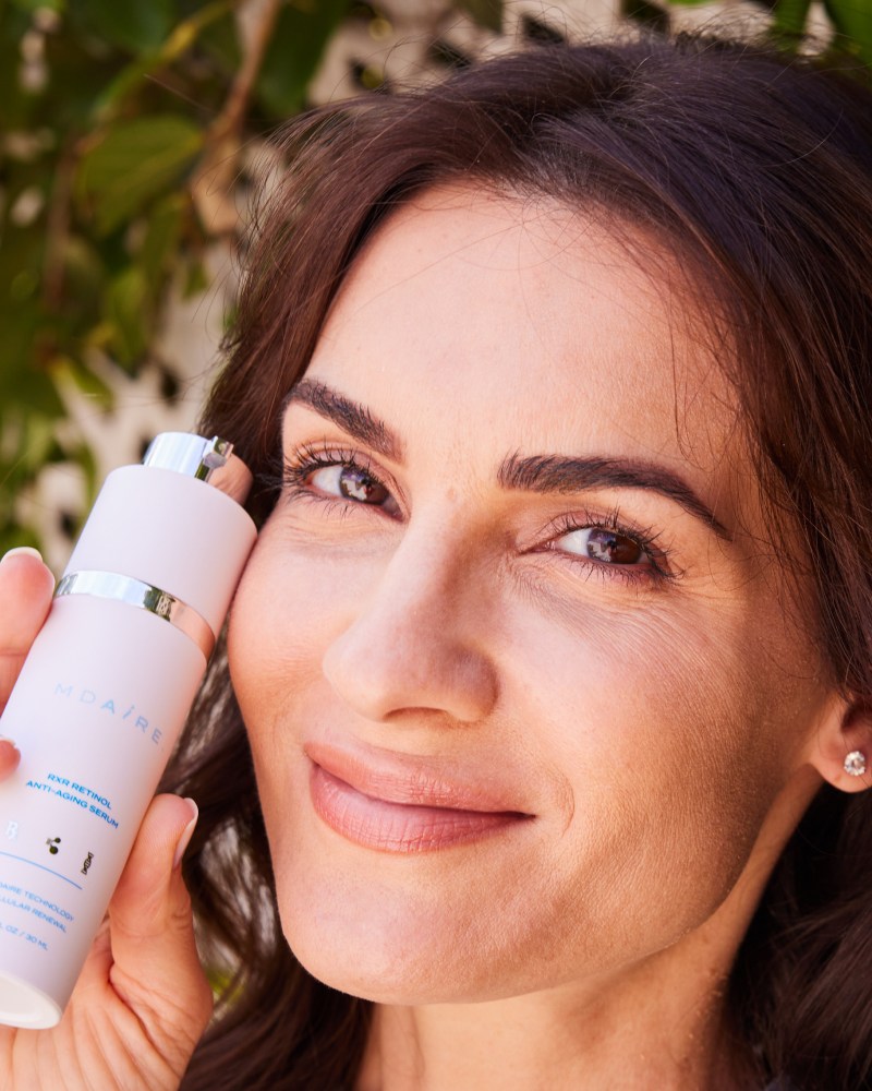 Complete System Bundle featuring woman smiling while holding RXR Retinol Anti-Aging Serum close to face gallery position 1