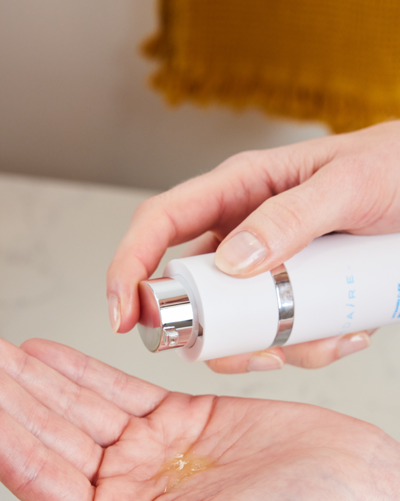 Hand dispensing Vitamin C-FK  Brightening Complex serum in gallery position 1 showcasing texture and packaging design